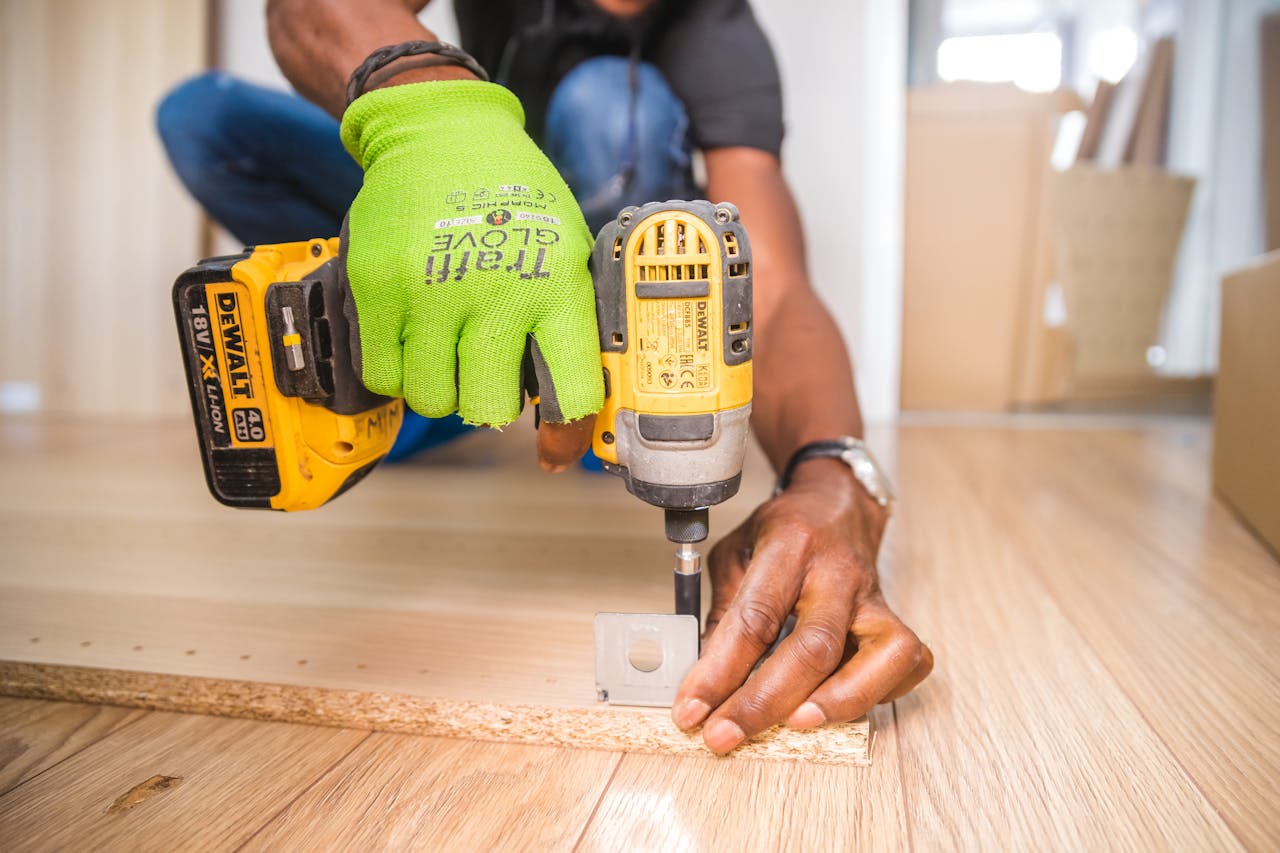 About Man using a power drill for home improvement on a wooden floor with precision.
